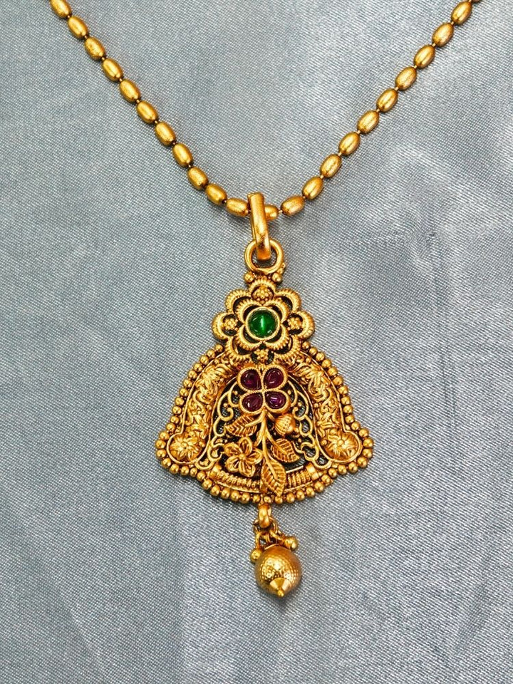 Close-up of an ornate traditional (Gold Polish) jewellery set and earrings with Pink & Green Colored Stones. Saree look completed with an elegant Colored Stone artificial jewelry piece. Festive Diwali outfit paired with a colorful Colored Stone necklace.