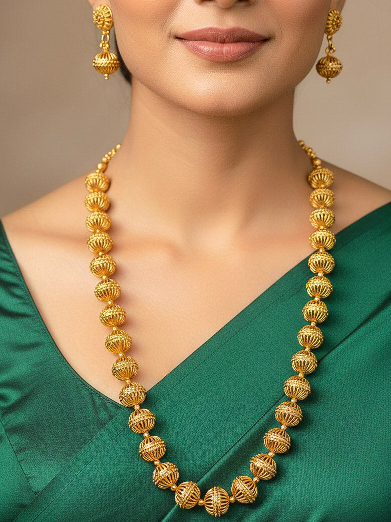 Close-up of a woman wearing an ornate traditional (Bright Gold Polish) Long jewellery set and earrings with Filigree Balls. Woman styling a vibrant Meenakari Filigree necklace with a festive saree. Festive celebration look enhanced with traditional Filigree jewelry.