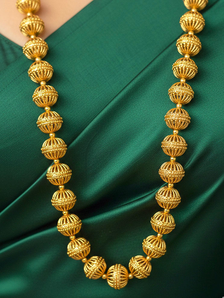 Close-up of a woman wearing an ornate traditional (Bright Gold Polish) Long jewellery set and earrings with Filigree Balls. Woman styling a vibrant Meenakari Filigree necklace with a festive saree. Festive celebration look enhanced with traditional Filigree jewelry.