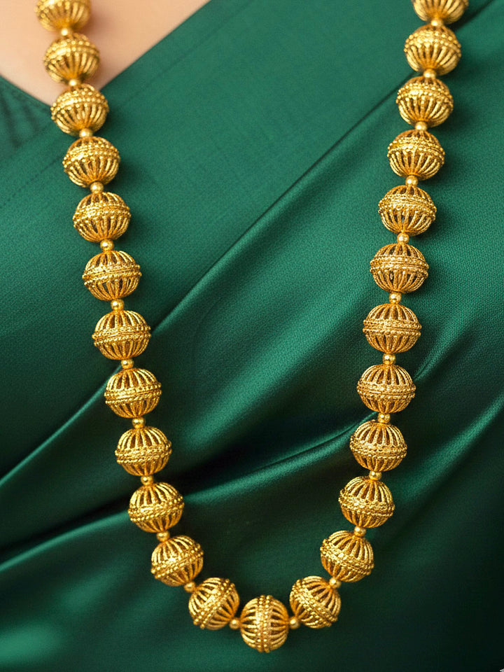 Close-up of a woman wearing an ornate traditional (Bright Gold Polish) Long jewellery set and earrings with Filigree Balls. Woman styling a vibrant Meenakari Filigree necklace with a festive saree. Festive celebration look enhanced with traditional Filigree jewelry.