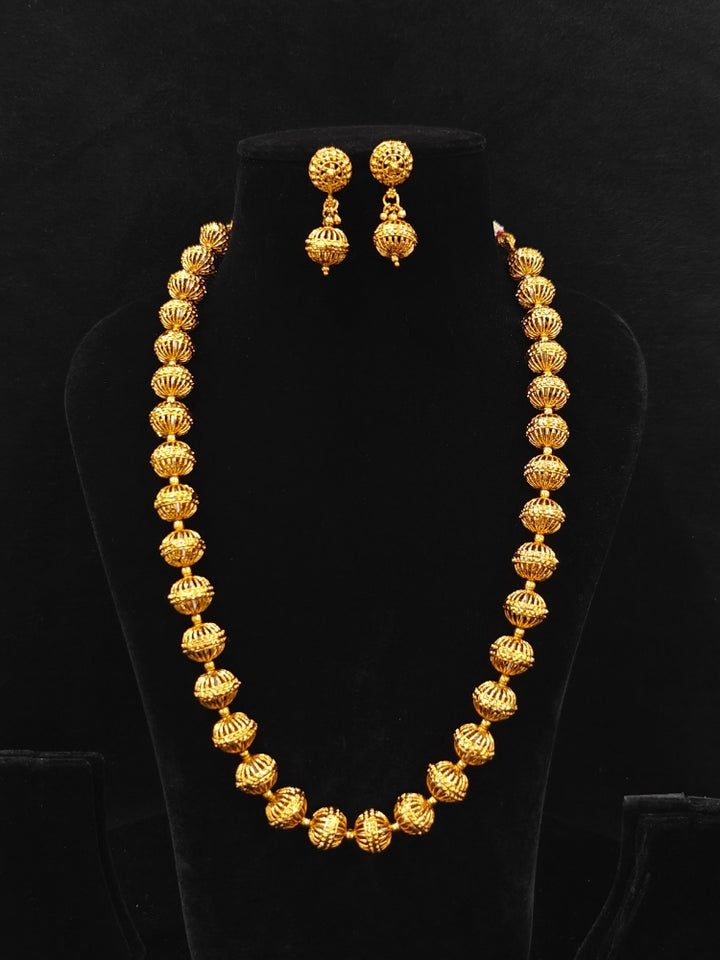 Close-up of an ornate traditional (Bright Gold Polish) Long jewellery set and earrings with Filigree Balls. Woman styling a vibrant Meenakari Filigree necklace with a festive saree. Festive celebration look enhanced with traditional Filigree jewelry.