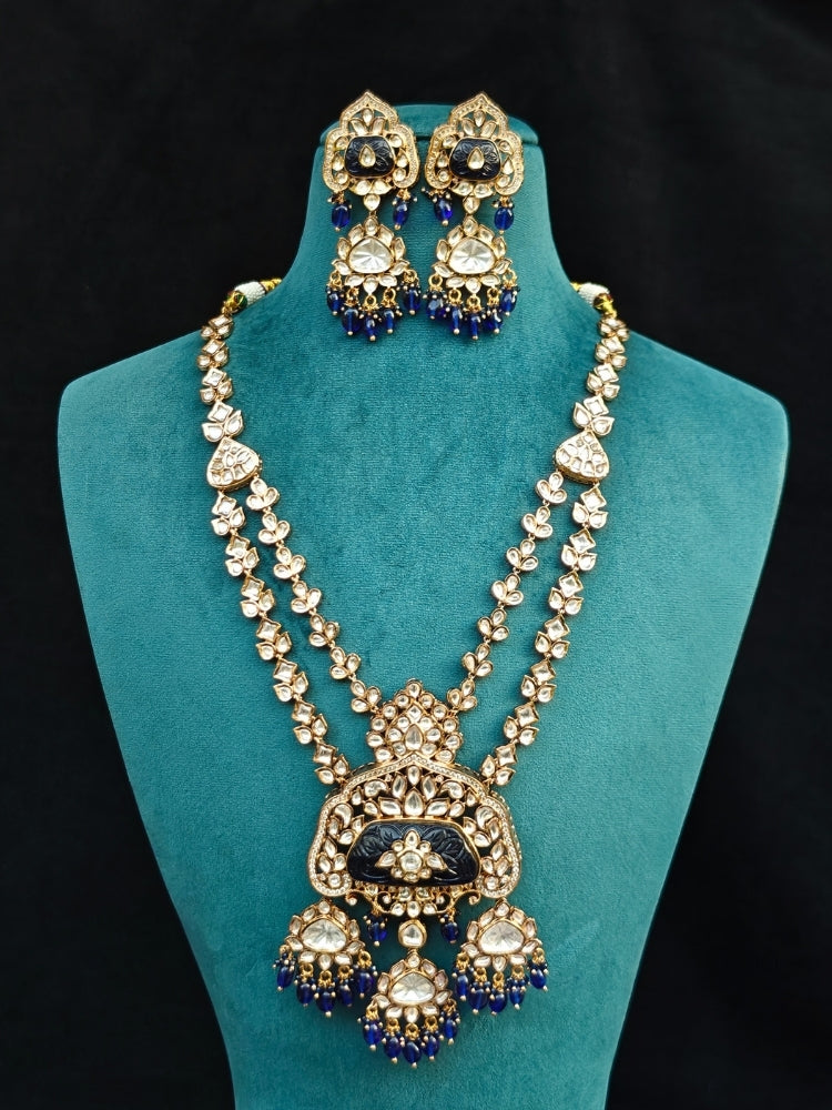 Close-up of an ornate traditional (Gold Polish) Long jewellery set and earrings with Polki, Colored Stones and Tumble Beads. Woman wearing trending Polki artificial jewelry for the wedding season in India. Festive celebration look completed with premium imitation Polki jewelry.