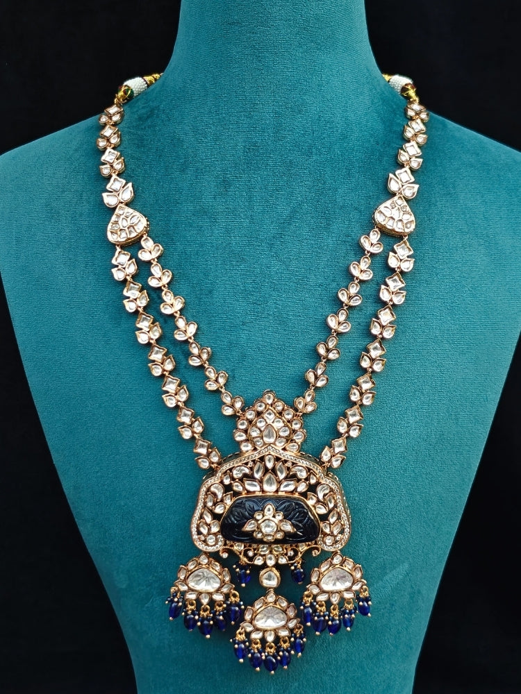 Close-up of an ornate traditional (Gold Polish) Long jewellery set and earrings with Polki, Colored Stones and Tumble Beads. Woman wearing trending Polki artificial jewelry for the wedding season in India. Festive celebration look completed with premium imitation Polki jewelry.