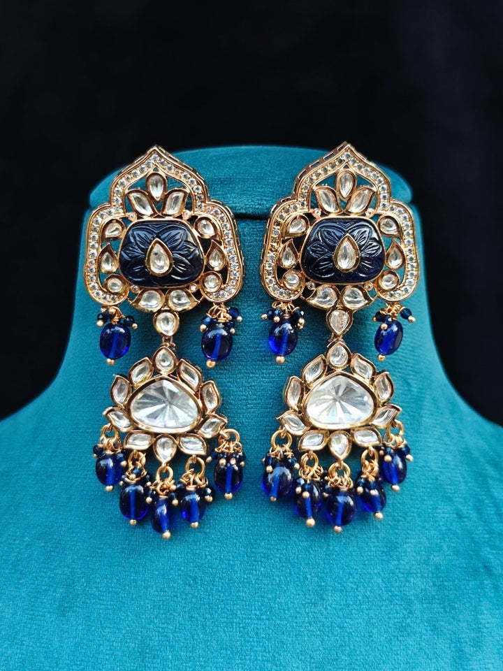 Close-up of an ornate traditional (Gold Polish) Long jewellery set and earrings with Polki, Colored Stones and Tumble Beads. Woman wearing trending Polki artificial jewelry for the wedding season in India. Festive celebration look completed with premium imitation Polki jewelry.