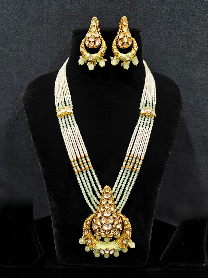 Close-up of an ornate traditional (Gold Polish) Mint Green Long jewellery set and earrings with Polki, Crystal Beads, Meenakari and Pearls. Festive Diwali look enhanced with a premium Polki artificial necklace. Saree styling inspiration with a Long Polki imitation jewelry piece.