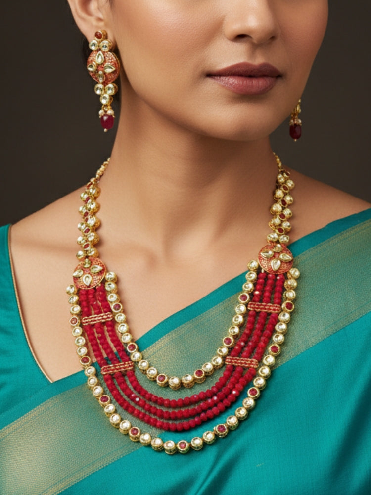 Close-up of a woman wearing an ornate traditional (Gold Polish) Red Kundan jewellery set and earrings with Kundan, Colored Stones, Meenakari and Crystal Beads. Mehendi ceremony look completed with a handcrafted Kundan jewelry set. Close-up of detailed Kundan stones in artificial wedding jewelry.