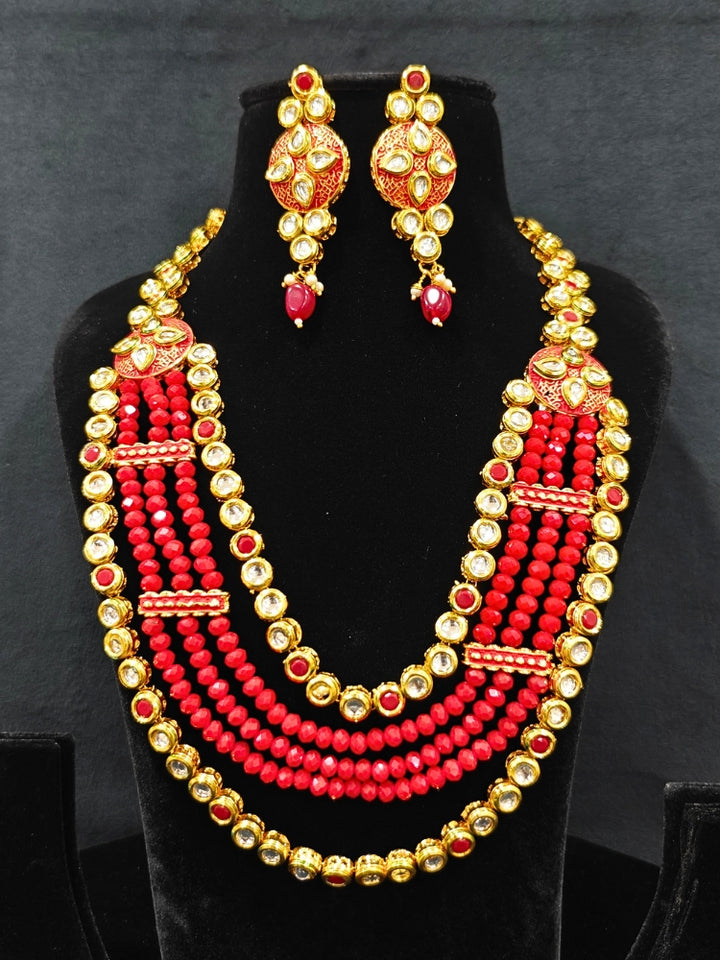Close-up of an ornate traditional (Gold Polish) Red Kundan jewellery set and earrings with Kundan, Colored Stones, Meenakari and Crystal Beads. Mehendi ceremony look completed with a handcrafted Kundan jewelry set. Close-up of detailed Kundan stones in artificial wedding jewelry.