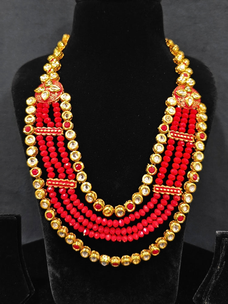 Close-up of an ornate traditional (Gold Polish) Red Kundan jewellery set and earrings with Kundan, Colored Stones, Meenakari and Crystal Beads. Mehendi ceremony look completed with a handcrafted Kundan jewelry set. Close-up of detailed Kundan stones in artificial wedding jewelry.