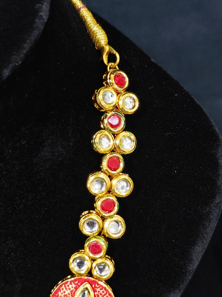 Close-up of an ornate traditional (Gold Polish) Red Kundan jewellery set and earrings with Kundan, Colored Stones, Meenakari and Crystal Beads. Mehendi ceremony look completed with a handcrafted Kundan jewelry set. Close-up of detailed Kundan stones in artificial wedding jewelry.