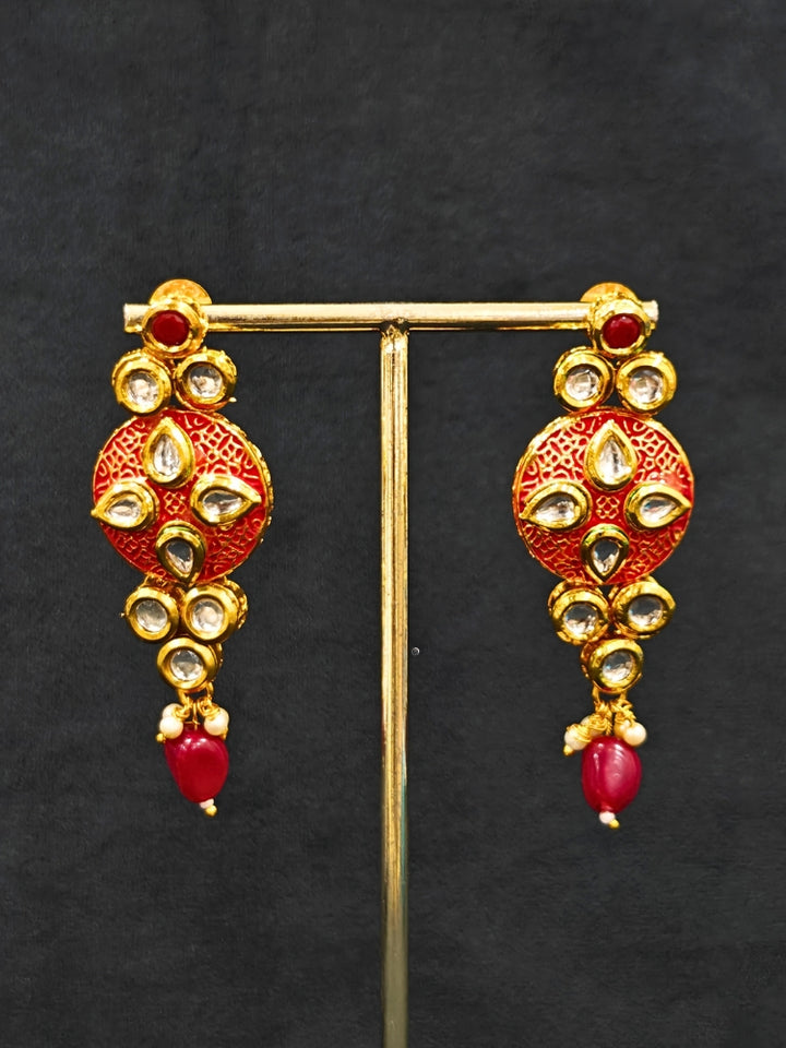 Close-up of an ornate traditional (Gold Polish) Red Kundan jewellery set and earrings with Kundan, Colored Stones, Meenakari and Crystal Beads. Mehendi ceremony look completed with a handcrafted Kundan jewelry set. Close-up of detailed Kundan stones in artificial wedding jewelry.