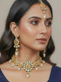 Close-up of a woman wearing an ornate traditional Peach Choker jewellery set and earrings and maangtikka with Kundan, Monalisa Stone, American Diamonds, Beads and Reverse American Diamonds and tumble stones. A graceful woman wearing a trending Colored Stone necklace for a 2026 wedding celebration. Elegant wedding jewelry look featuring a premium artificial Colored Stone necklace.