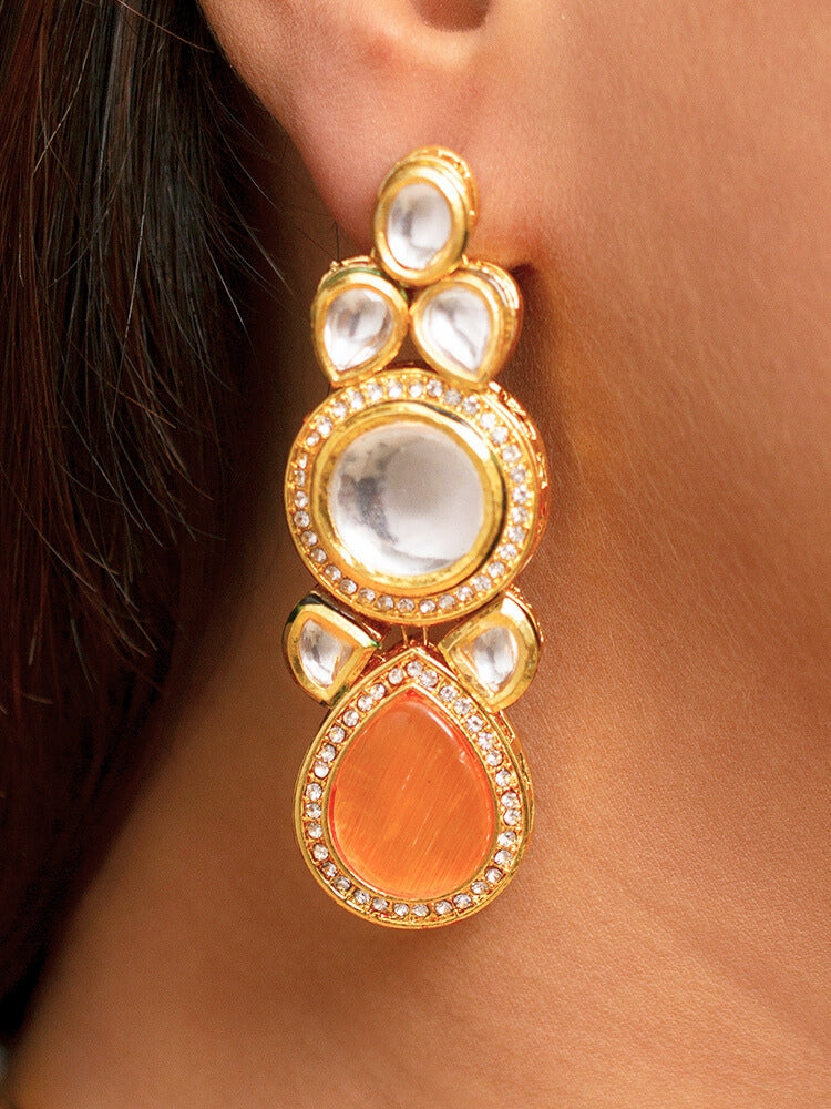 Close-up of a woman wearing an ornate traditional (Gold Polish) Peach Collar jewellery set and earrings and maangtikka with Kundan and American Diamonds. Woman wearing trending Kundan artificial jewelry for wedding season in India. Bride wearing a royal Kundan artificial necklace for wedding rituals.