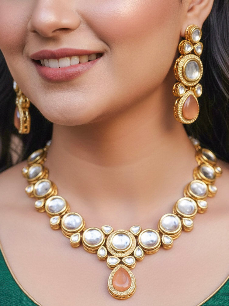 Close-up of a woman wearing an ornate traditional (Gold Polish) Peach Collar jewellery set and earrings and maangtikka with Kundan and American Diamonds. Woman wearing trending Kundan artificial jewelry for wedding season in India. Bride wearing a royal Kundan artificial necklace for wedding rituals.