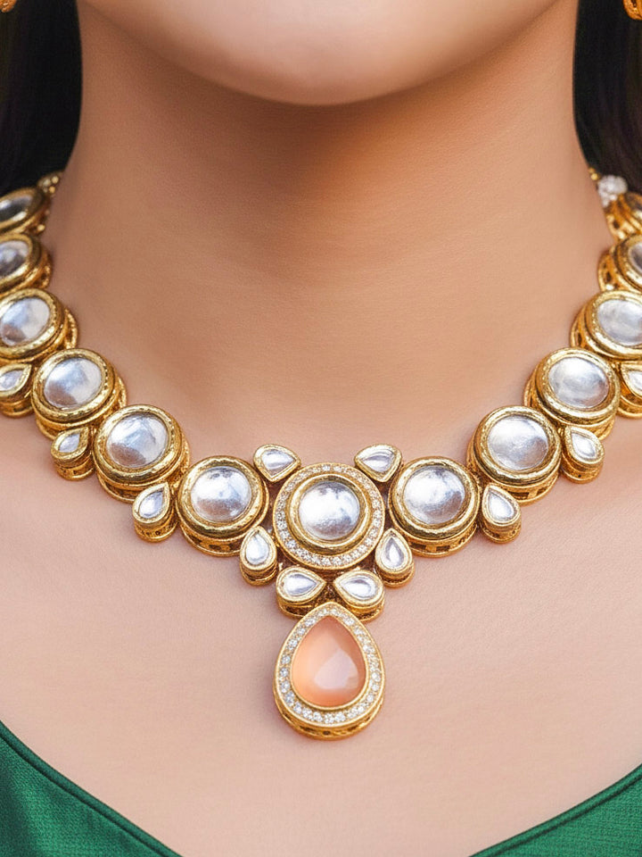 Close-up of a woman wearing an ornate traditional (Gold Polish) Peach Collar jewellery set and earrings and maangtikka with Kundan and American Diamonds. Woman wearing trending Kundan artificial jewelry for wedding season in India. Bride wearing a royal Kundan artificial necklace for wedding rituals.