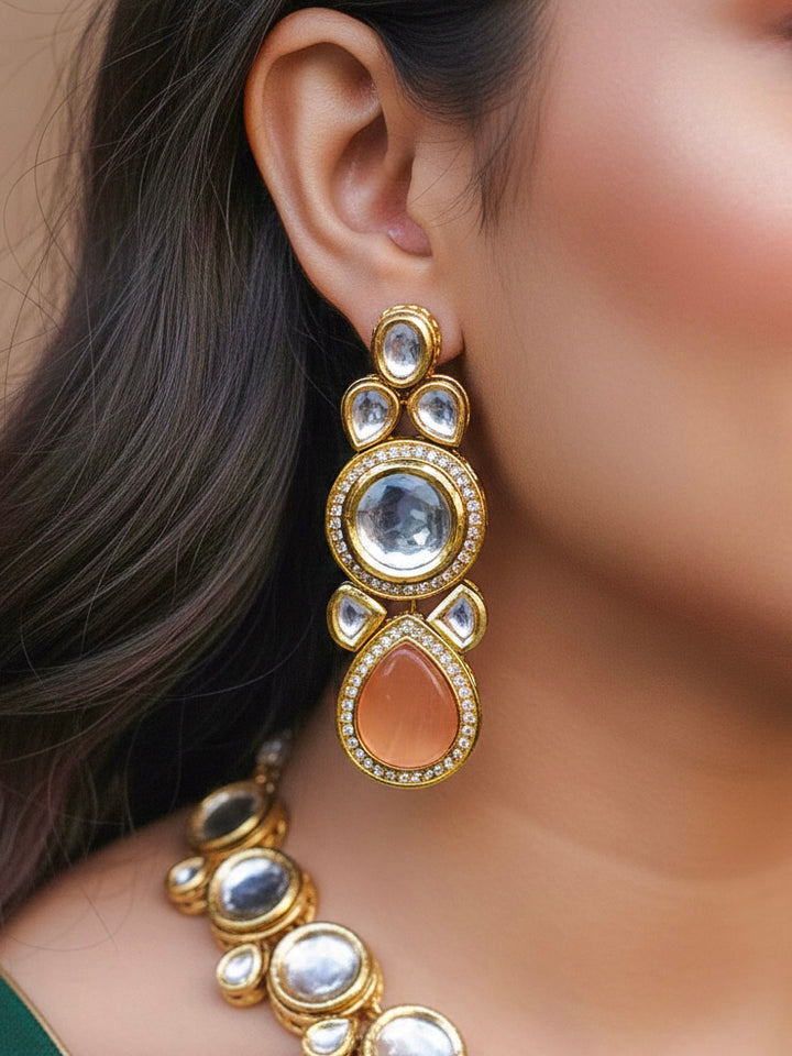 Close-up of a woman wearing an ornate traditional (Gold Polish) Peach Collar jewellery set and earrings and maangtikka with Kundan and American Diamonds. Woman wearing trending Kundan artificial jewelry for wedding season in India. Bride wearing a royal Kundan artificial necklace for wedding rituals.