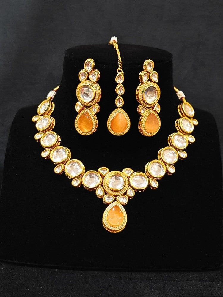 Close-up of an ornate traditional (Gold Polish) Peach Collar jewellery set and earrings and maangtikka with Kundan and American Diamonds. A trending Kundan artificial jewelry for wedding season in India. Bride wearing a royal Kundan artificial necklace for wedding rituals.