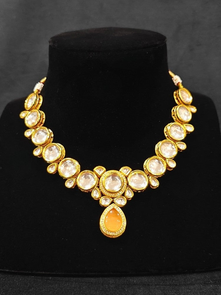 Close-up of an ornate traditional (Gold Polish) Peach Collar jewellery set and earrings and maangtikka with Kundan and American Diamonds. A trending Kundan artificial jewelry for wedding season in India. Bride wearing a royal Kundan artificial necklace for wedding rituals.