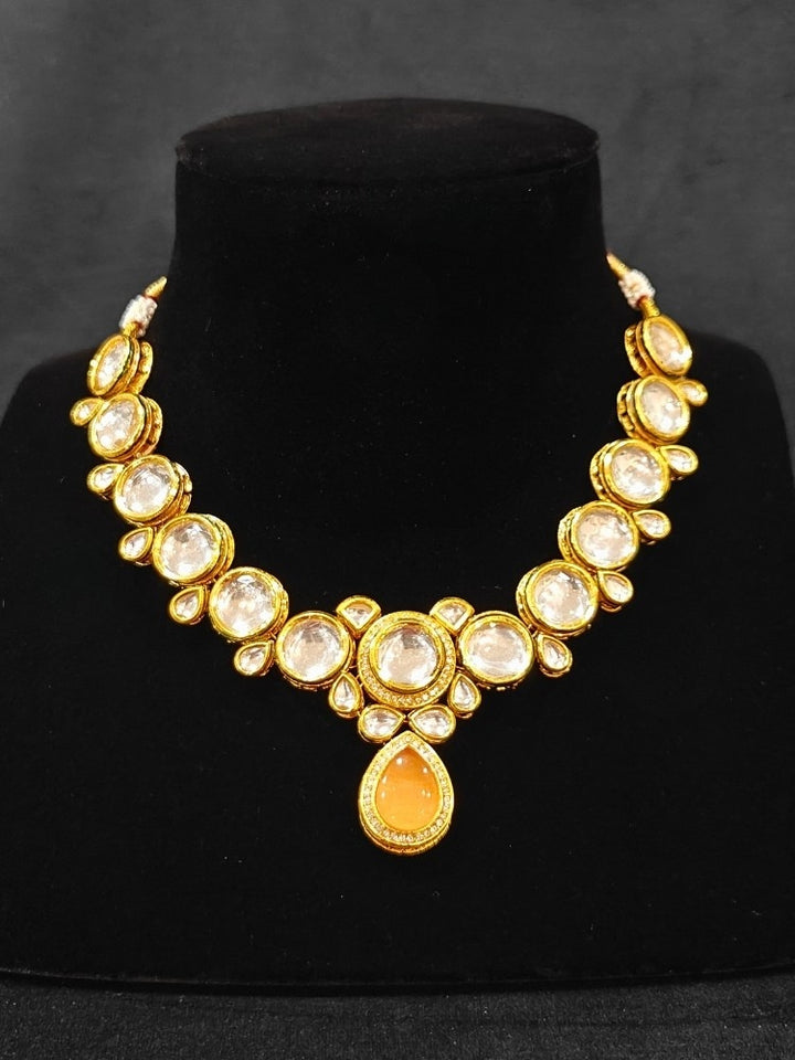 Close-up of an ornate traditional (Gold Polish) Peach Collar jewellery set and earrings and maangtikka with Kundan and American Diamonds. A trending Kundan artificial jewelry for wedding season in India. Bride wearing a royal Kundan artificial necklace for wedding rituals.
