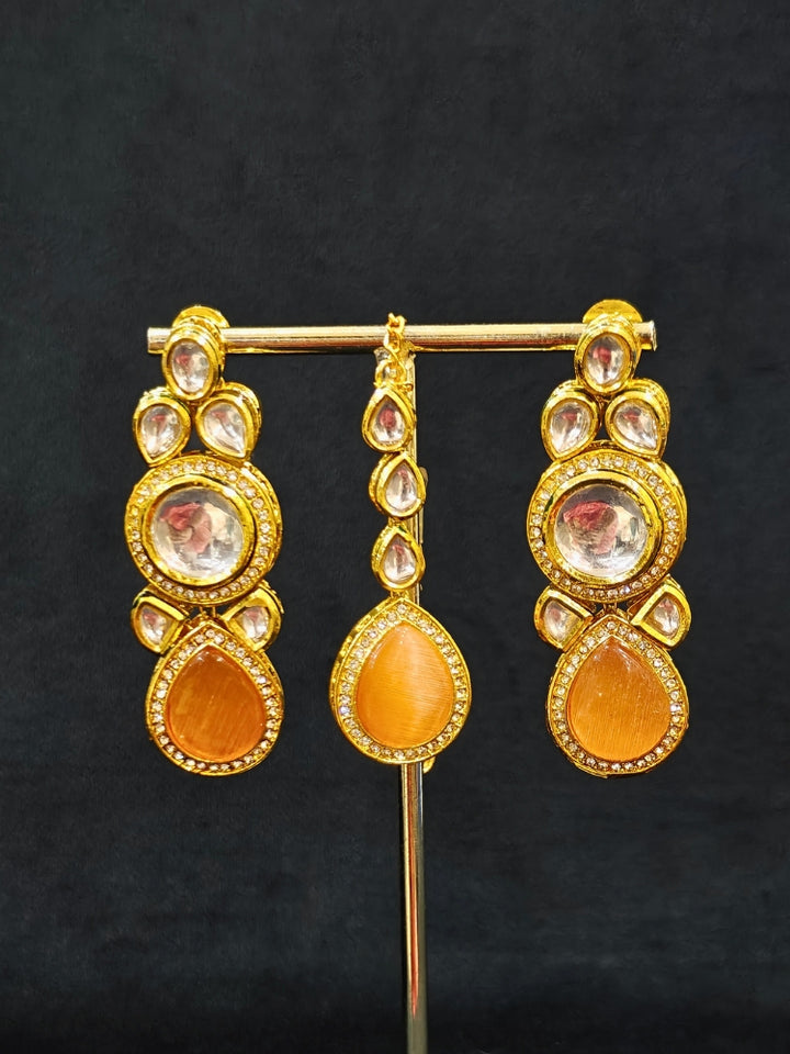 Close-up of an ornate traditional (Gold Polish) Peach Collar jewellery set and earrings and maangtikka with Kundan and American Diamonds. A trending Kundan artificial jewelry for wedding season in India. Bride wearing a royal Kundan artificial necklace for wedding rituals.