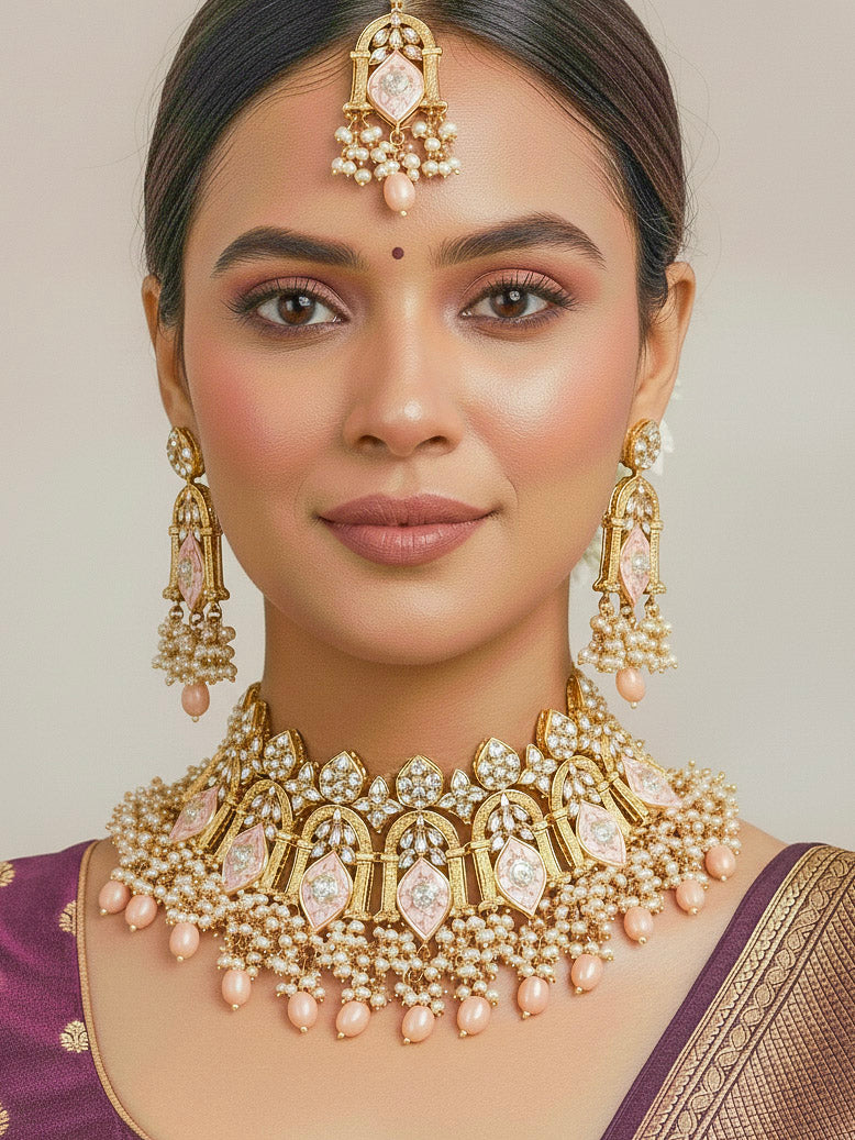 Close-up of a woman wearing an ornate traditional (Gold Polish) Peach Choker jewellery set and earrings and maangtikka with Kundan, Meenakari, Crystal beads and Tumble beads. Close-up of intricate Kundan craftsmanship in artificial bridal jewelry. Bride wearing a traditional Kundan artificial necklace set for her wedding ceremony.