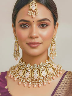 Close-up of a woman wearing an ornate traditional (Gold Polish) Peach Choker jewellery set and earrings and maangtikka with Kundan, Meenakari, Crystal beads and Tumble beads. Close-up of intricate Kundan craftsmanship in artificial bridal jewelry. Bride wearing a traditional Kundan artificial necklace set for her wedding ceremony.