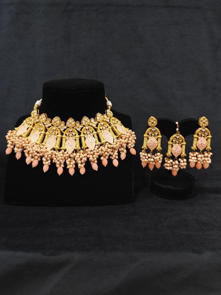 Close-up of an ornate traditional (Gold Polish) Peach Choker jewellery set and earrings and maangtikka with Kundan, Meenakari, Crystal beads and Tumble beads. Close-up of intricate Kundan craftsmanship in artificial bridal jewelry. A traditional Kundan artificial necklace set for her wedding ceremony.