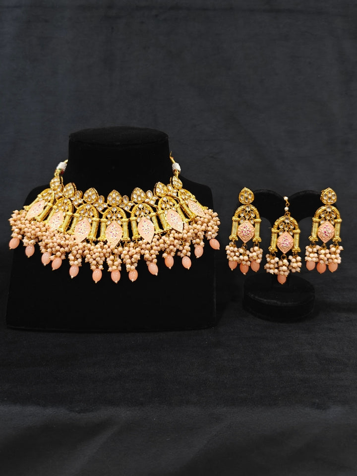 Close-up of an ornate traditional (Gold Polish) Peach Choker jewellery set and earrings and maangtikka with Kundan, Meenakari, Crystal beads and Tumble beads. Close-up of intricate Kundan craftsmanship in artificial bridal jewelry. A traditional Kundan artificial necklace set for her wedding ceremony.