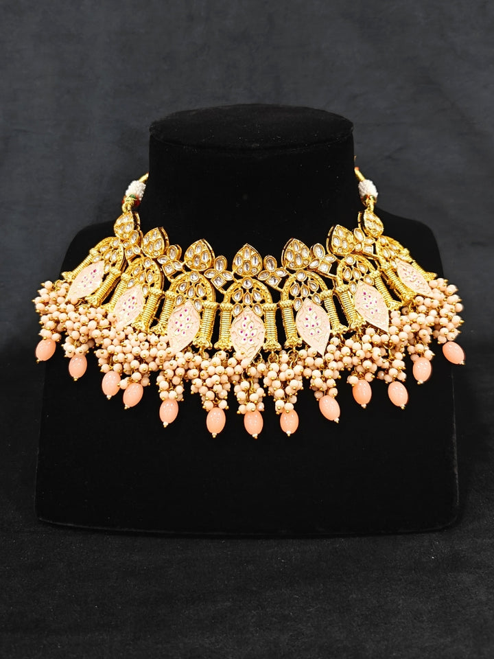 Close-up of an ornate traditional (Gold Polish) Peach Choker jewellery set and earrings and maangtikka with Kundan, Meenakari, Crystal beads and Tumble beads. Close-up of intricate Kundan craftsmanship in artificial bridal jewelry. A traditional Kundan artificial necklace set for her wedding ceremony.