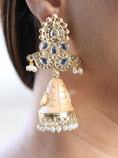 Close-up of a woman wearing an ornate traditional Peach Kundan Earrings with Pearls, Kundan and Meenakari. Close-up of anti-tarnish artificial Kundan earrings for festive celebrations. Festive saree look completed with premium imitation Kundan earrings.