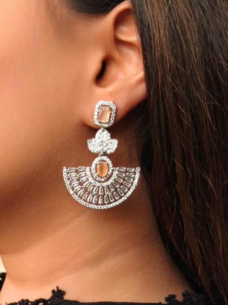 Close-up of a woman wearing an ornate Western (Silver Polish) Peach Diamond Earrings with American Diamond and Colored Stones. Reception-ready look featuring a statement American diamond Earrings set. Elegant wedding jewelry look featuring a premium artificial American diamond Earrings.