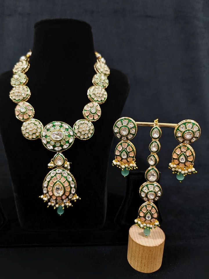 Close-up of an ornate traditional Peach Jewelry Set, Earrings and Mangtikka with Kundan and Colored Stones. Bride wearing a traditional Kundan artificial necklace set for her wedding ceremony. Woman wearing trending Kundan artificial jewelry for wedding season in India.
