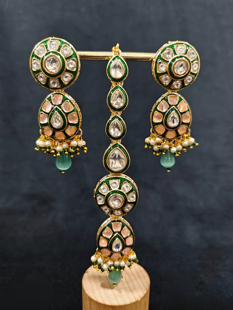 Close-up of an ornate traditional Peach Jewelry Set, Earrings and Mangtikka with Kundan and Colored Stones. Bride wearing a traditional Kundan artificial necklace set for her wedding ceremony. Woman wearing trending Kundan artificial jewelry for wedding season in India.