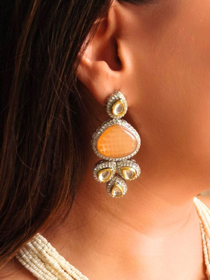 A woman in a gold embroidered outfit smiles, showcasing the Peacoski Peach Tamanna Necklace Set and matching earrings. Her soft makeup highlights the elegance of this statement jewelry ensemble.