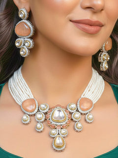 Close-up of a woman wearing an ornate traditional Peach Collar Kundan jewellery set and earrings with American diamonds, Monalisa stone, Pearls, Kundan and Colored Stones. Festive Diwali outfit paired with a premium Kundan jewelry piece. Woman wearing trending Kundan artificial jewelry for wedding season in India.