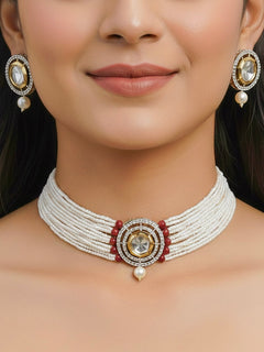 Close-up of a woman wearing an ornate traditional Red Choker jewellery set and earrings with Kundan, American Diamond, Crystal Beads and Pearls. Festive saree styling with a premium artificial Pearls necklace. Mehendi ceremony look completed with a handcrafted Pearls jewelry set.