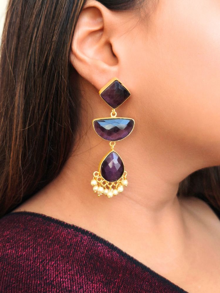 A close-up of a womans ear wearing Penelope Purple Earrings—large, gold-framed Purple earrings with Monalisa stones and white pearl accents—paired with a gold-embroidered Maroon outfit, perfect for a wedding ceremony.