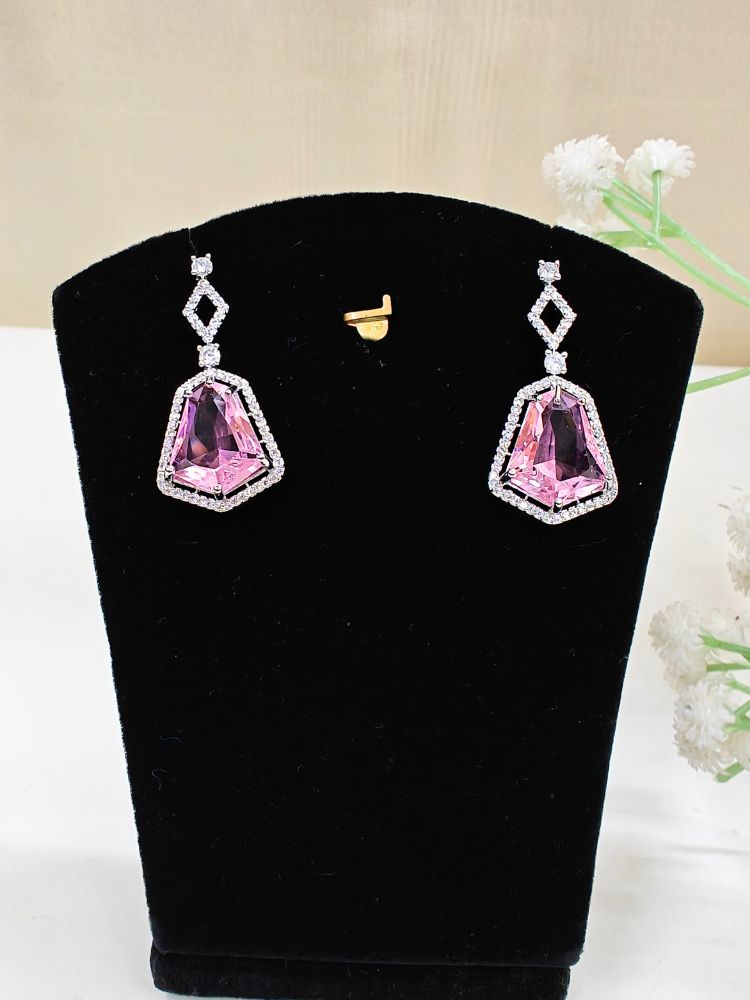 A woman showcases the Angela Pink Necklace Set, featuring matching jewelry with bold Pink stones and sparkling American Diamonds on both drop earrings and a geometric pendant necklace for a striking look. set on a black dummy. 