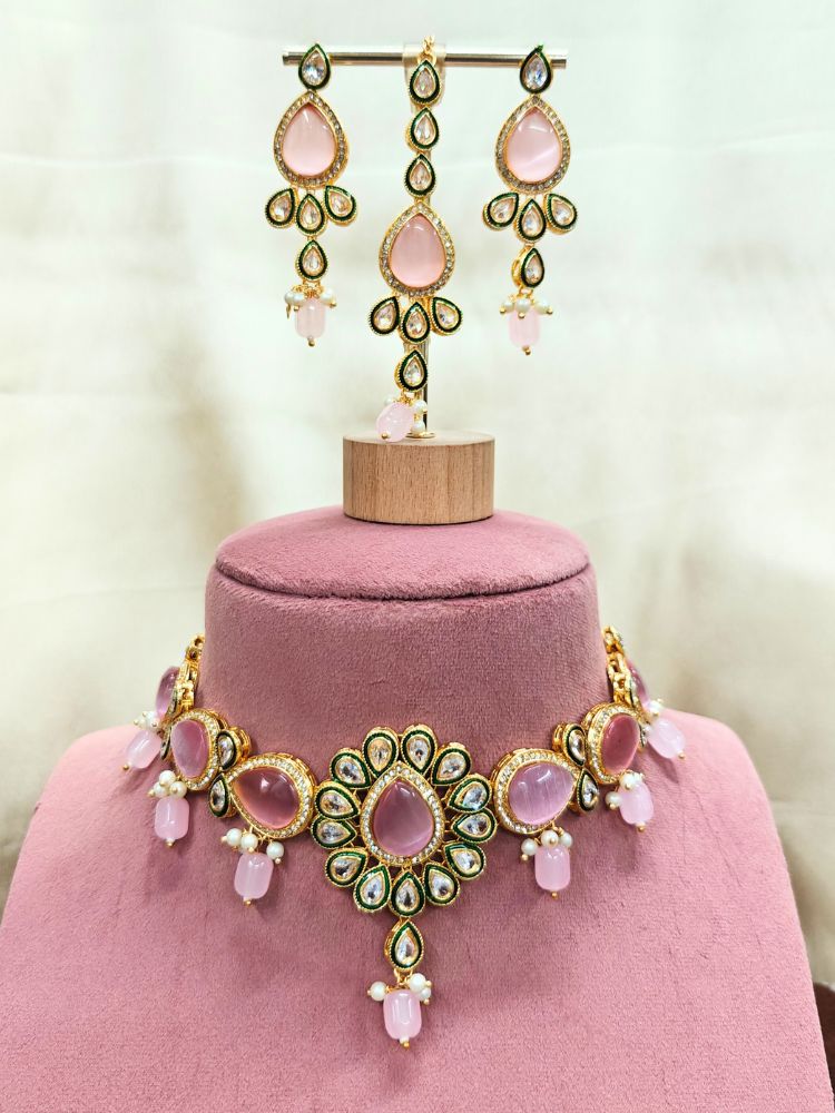 The Pink Aurora Necklace Set is displayed on a pink stand, featuring Pink Monalisa stones, small white pearls, and american diamonds in an ornate floral design.