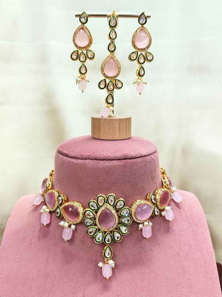 The Pink Aurora Necklace Set is displayed on a pink stand, featuring Pink Monalisa stones, small white pearls, and american diamonds in an ornate floral design.