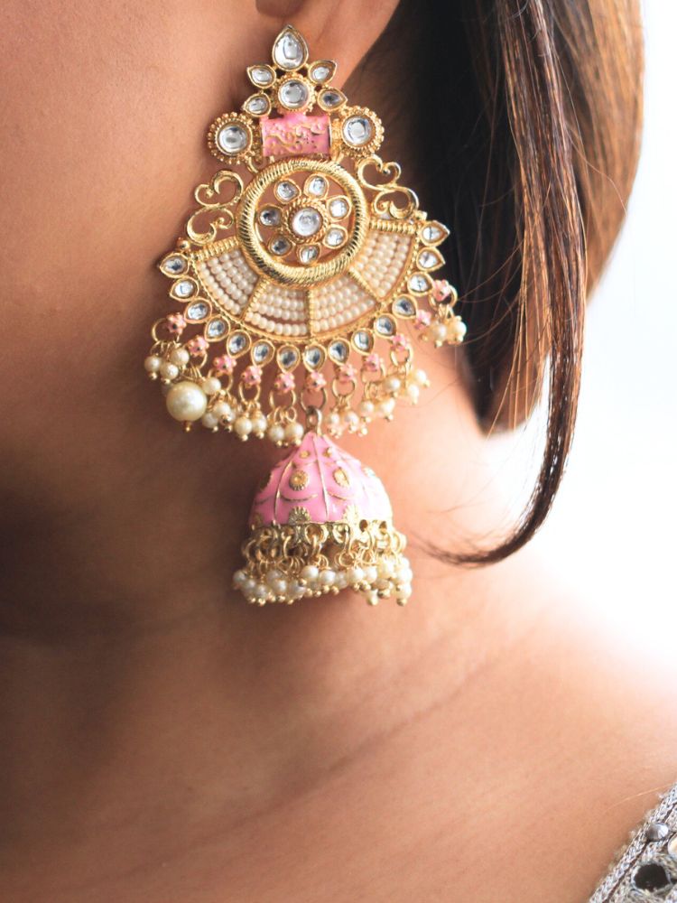 Close-up of a woman wearing an ornate traditional Pink Meenakari gold Long Earrings with Pearls, Kundan and Meenakari. Woman wearing statement artificial Meenakari earrings for a wedding guest look in India. Woman styling long artificial Meenakari earrings with a lehenga for a wedding.