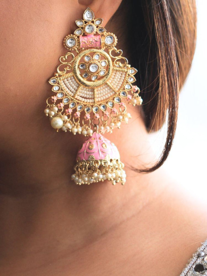 Close-up of a woman wearing an ornate traditional Pink Meenakari gold Long Earrings with Pearls, Kundan and Meenakari. Woman wearing statement artificial Meenakari earrings for a wedding guest look in India. Woman styling long artificial Meenakari earrings with a lehenga for a wedding.