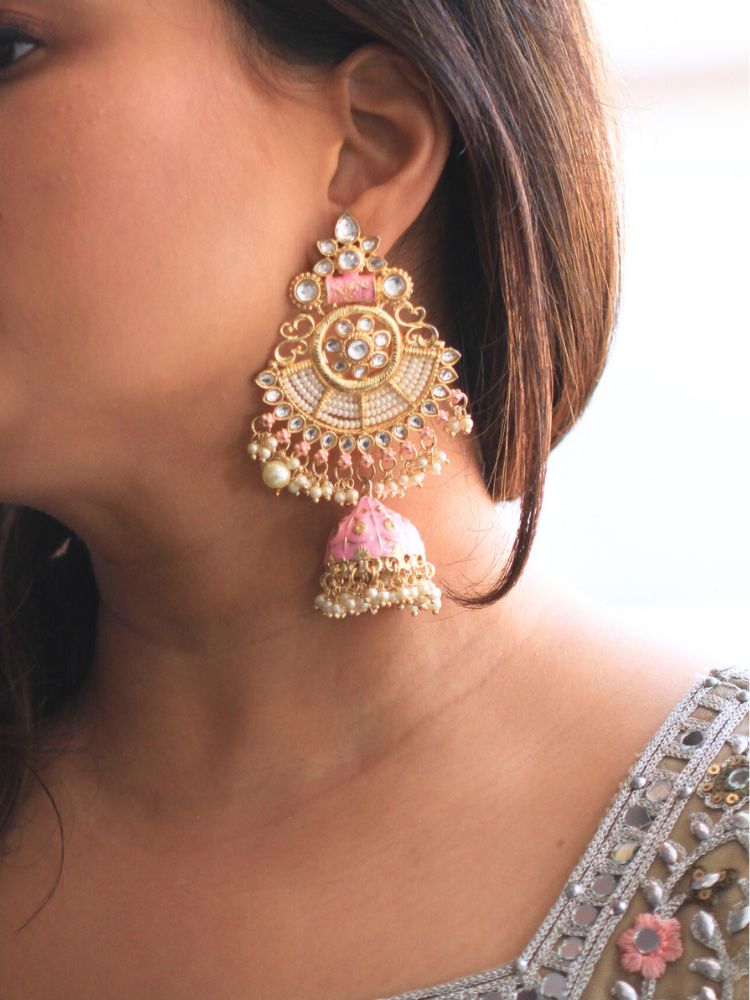 Close-up of a woman wearing an ornate traditional Pink Meenakari gold Long Earrings with Pearls, Kundan and Meenakari. Woman wearing statement artificial Meenakari earrings for a wedding guest look in India. Woman styling long artificial Meenakari earrings with a lehenga for a wedding.
