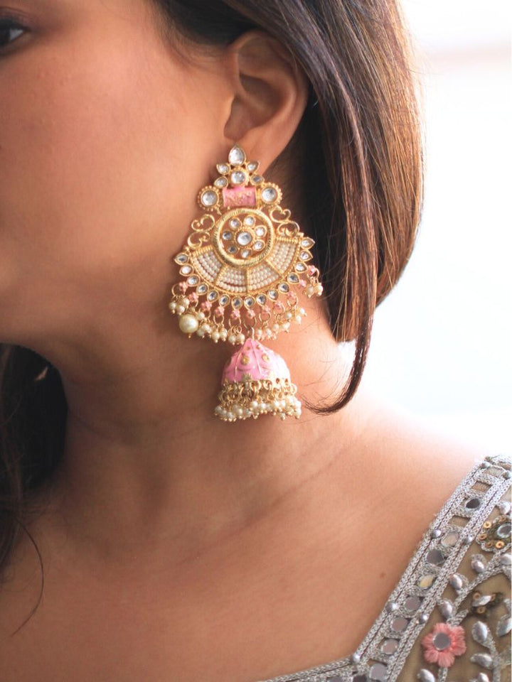 Close-up of a woman wearing an ornate traditional Pink Meenakari gold Long Earrings with Pearls, Kundan and Meenakari. Woman wearing statement artificial Meenakari earrings for a wedding guest look in India. Woman styling long artificial Meenakari earrings with a lehenga for a wedding.