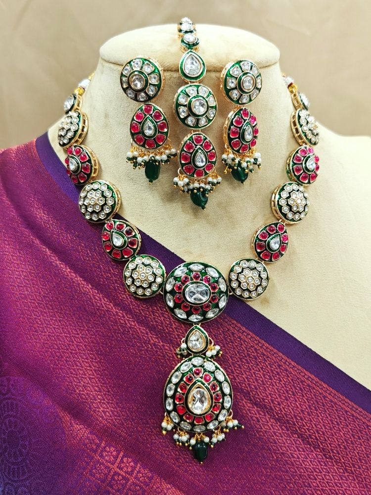 Close-up of a woman wearing an ornate traditional Pink Jewelry Set, Earrings and Mangtikka with Kundan and Colored Stones. Bride wearing a traditional Kundan artificial necklace set for her wedding ceremony. Woman wearing trending Kundan artificial jewelry for wedding season in India.