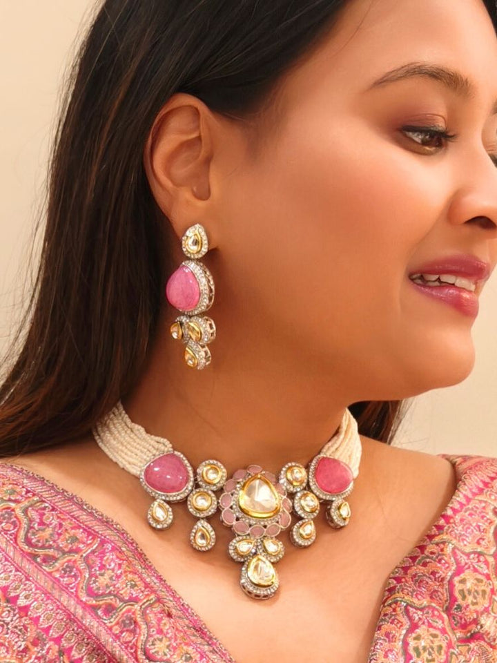 A woman in a Pink embroidered outfit smiles, showcasing the Peacoski Pink Tamanna Necklace Set and matching earrings. Her soft makeup highlights the elegance of this statement jewelry ensemble.