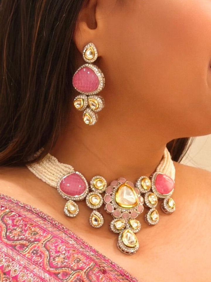 A woman in a Pink embroidered outfit smiles, showcasing the Peacoski Pink Tamanna Necklace Set and matching earrings. Her soft makeup highlights the elegance of this statement jewelry ensemble.