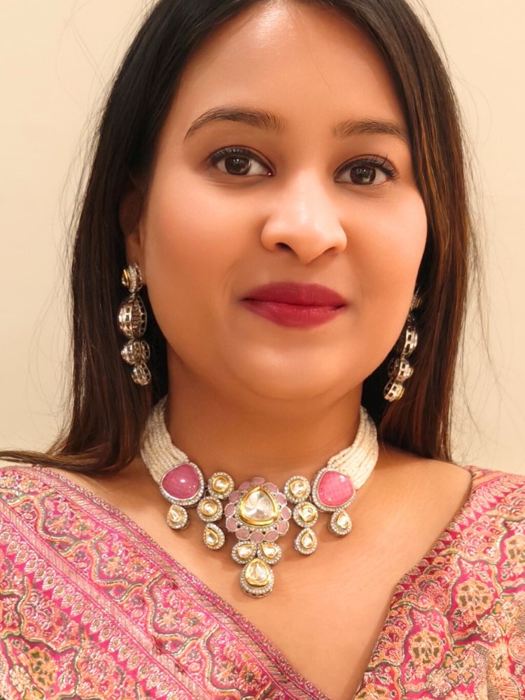 A woman in a Pink embroidered outfit smiles, showcasing the Peacoski Pink Tamanna Necklace Set and matching earrings. Her soft makeup highlights the elegance of this statement jewelry ensemble.