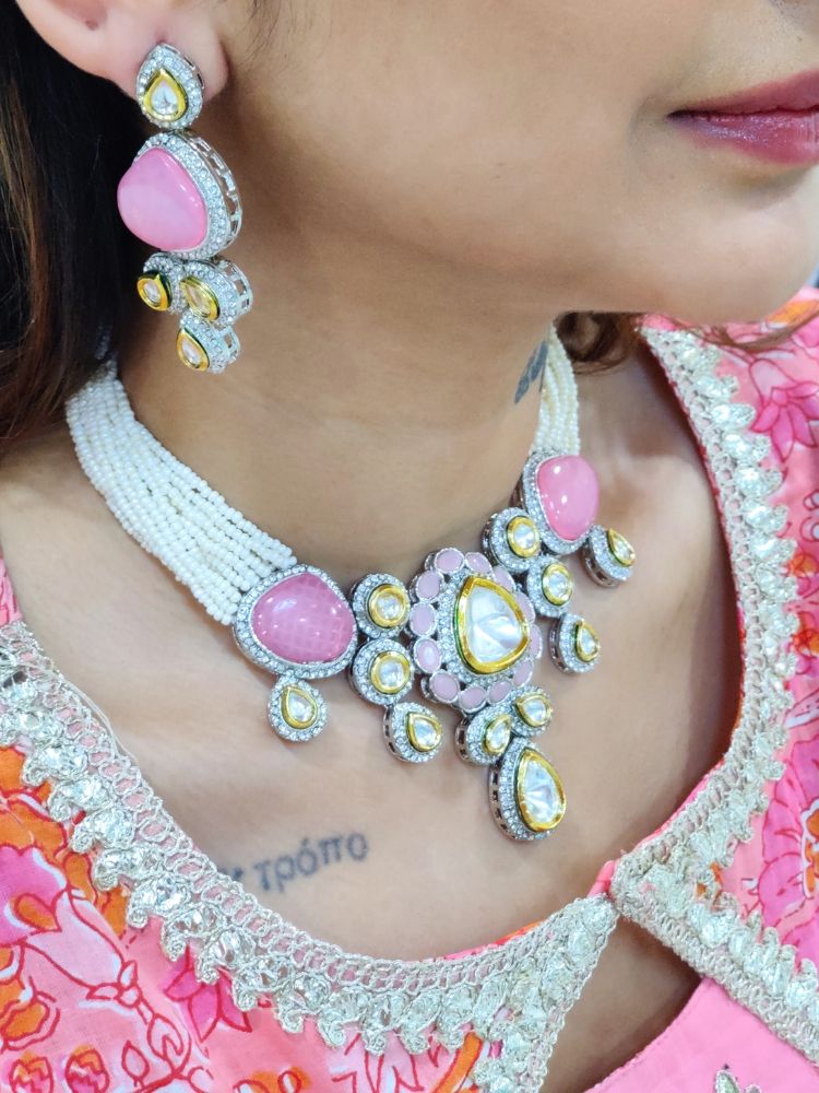 A woman in a Pink embroidered outfit smiles, showcasing the Peacoski Pink Tamanna Necklace Set and matching earrings. Her soft makeup highlights the elegance of this statement jewelry ensemble.