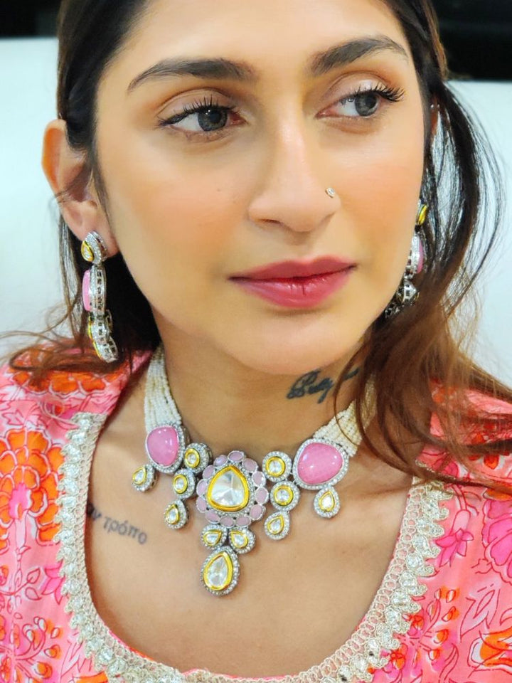 A woman in a PInk embroidered outfit smiles, showcasing the Peacoski Pink Tamanna Necklace Set and matching earrings. Her soft makeup highlights the elegance of this statement jewelry ensemble.