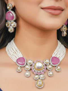 Close-up of a woman wearing an ornate traditional Pink Collar Kundan jewellery set and earrings with American diamonds, Monalisa stone, Pearls, Kundan and Colored Stones. Festive Diwali outfit paired with a premium Kundan jewelry piece. Woman wearing trending Kundan artificial jewelry for wedding season in India.